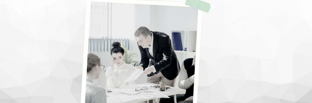 Chef zeigt Mitarbeiterinnen ein Blatt. Mitarbeiterin fühlt sich belehrt.